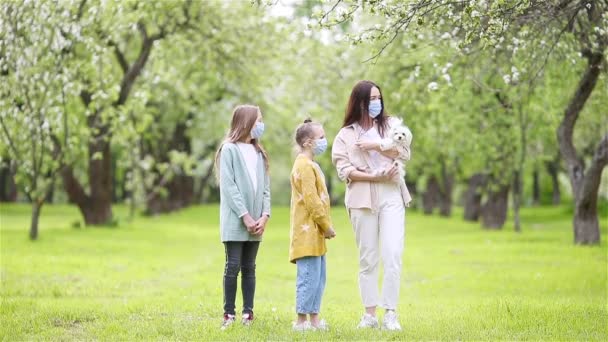 Familj till mor och döttrar i blommande körsbärsträdgård i masker — Stockvideo