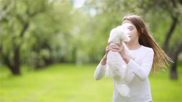Małe uśmiechnięte dziewczynki bawią się i przytulają szczeniaka w parku — Wideo stockowe