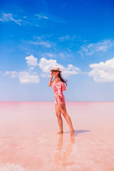 Vrouw in muts lopen op een roze zoutmeer op een zonnige zomerdag. — Stockfoto