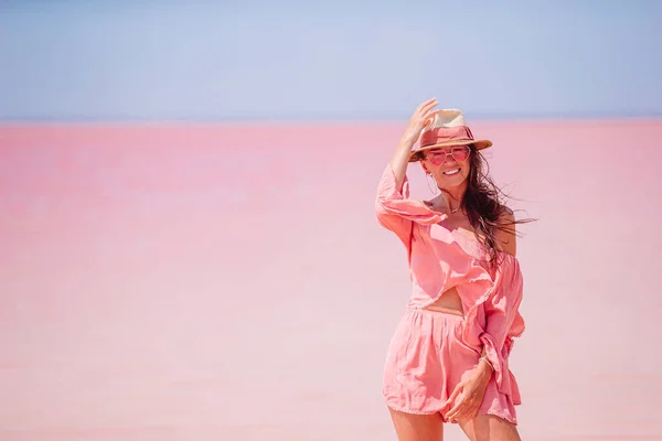 Mujer en sombrero caminar en un lago de sal rosa en un día soleado de verano. —  Fotos de Stock