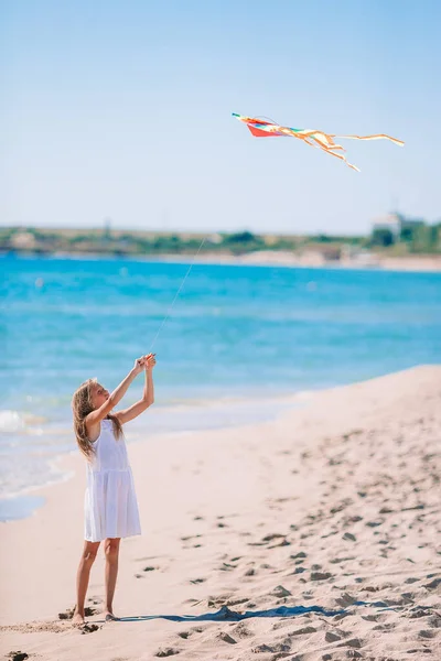 Kleines Mädchen lässt bei Sonnenuntergang einen Drachen am Strand steigen — Stockfoto