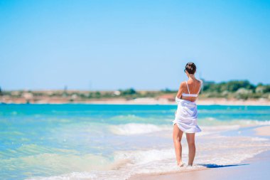 Plajda beyazlar içindeki genç kadın.