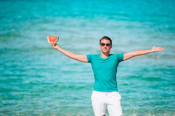 Uomo felice divertirsi sulla spiaggia e mangiare anguria — Foto Stock