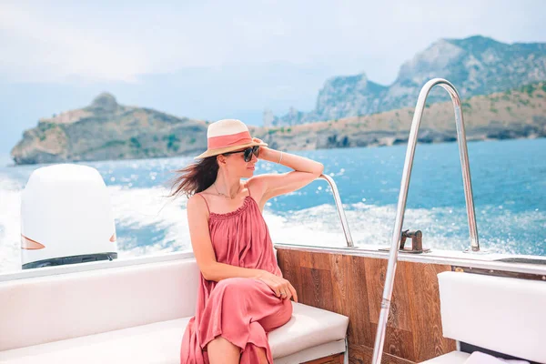 Woman in hat and dress sailing on boat in clear open sea — Stock Photo, Image