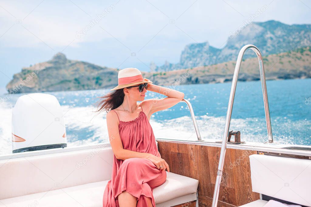 Woman in hat and dress sailing on boat in clear open sea