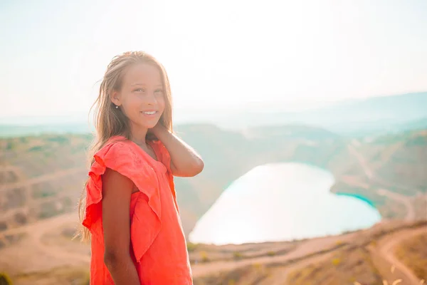 Little girl near the lake at the day time with amazing nature on background — Stock Photo, Image