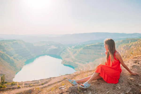 Klein meisje in de buurt van het meer op de dag tijd met verbazingwekkende natuur op de achtergrond — Stockfoto