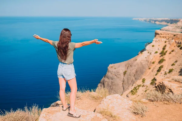 Tourist woman outdoor on edge of cliff seashore — Stock Photo, Image