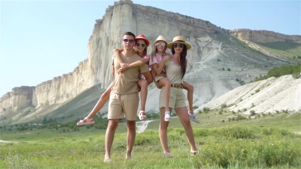 Счастливая семья из четырех человек, гуляющих по горам — стоковое видео