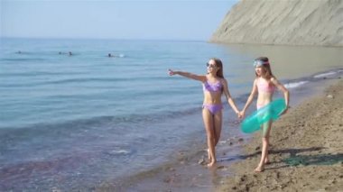 Küçük mutlu komik kızlar tropikal plajda birlikte oynarken çok eğlenirler..