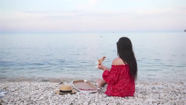 Kvinna som har picknick med pizza på stranden — Stockvideo