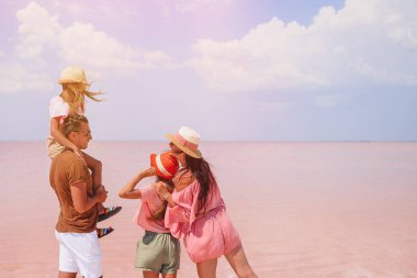 Güneşli bir yaz gününde pembe bir tuz gölünde aile yürüyüşü.