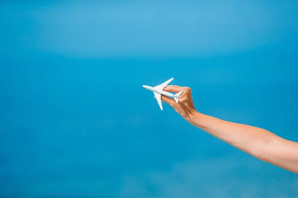 女性の手にミニチュアのおもちゃの飛行機。飛行機で旅行する。旅行や観光のための概念的なイメージ. — ストック写真