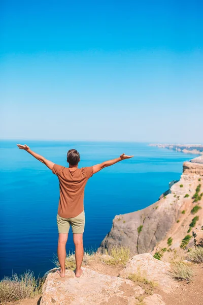 Uomo turistico all'aperto sul bordo della scogliera sul mare — Foto Stock