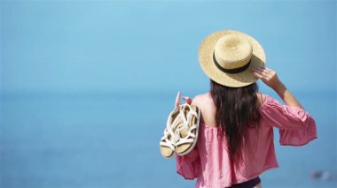 Genç ve güzel bir kadın tropik deniz kıyısında eğleniyor. Mutlu kız arka planda mavi gökyüzü ve denizdeki turkuaz su