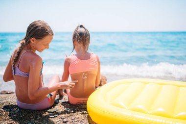 Ultraviyole koruma. Kız kardeşi küçük kız kardeşinin burnuna güneş kremi sürüyor.