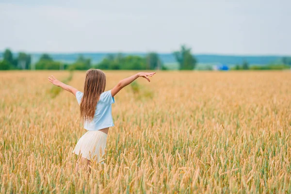 Glückliches kleines Mädchen, das in goldenen Weizenfeldern wandelt — Stockfoto