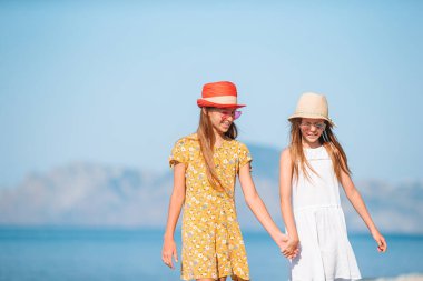 Küçük mutlu komik kızlar tropikal plajda birlikte oynarken çok eğlenirler..