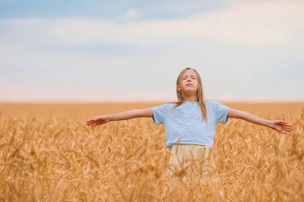 Glückliches kleines Mädchen, das in goldenen Weizenfeldern wandelt — Stockfoto