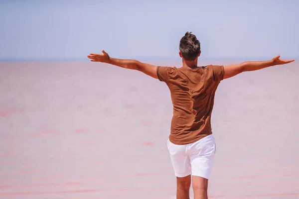 Tourist man walk on a pink salt lake on a sunny summer day. — Stock Photo, Image