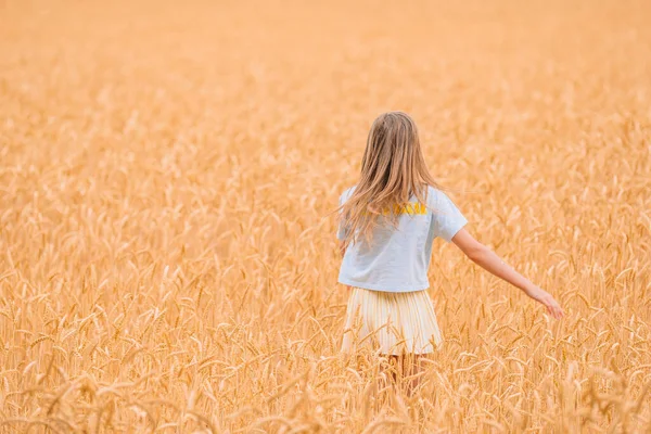 幸せな女の子は小麦の黄金のフィールドを歩く — ストック写真