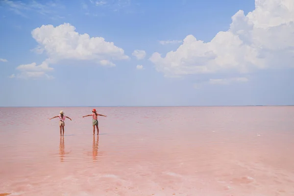Meisjes op een roze zoutmeer op een zonnige zomerdag. — Stockfoto