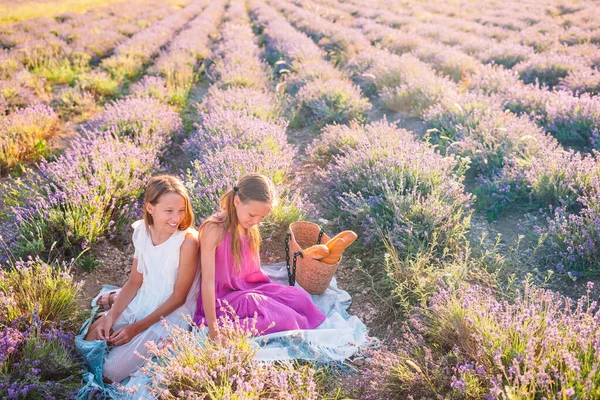 Crianças no campo de flores de lavanda ao pôr do sol em vestido branco e chapéu — Fotografia de Stock