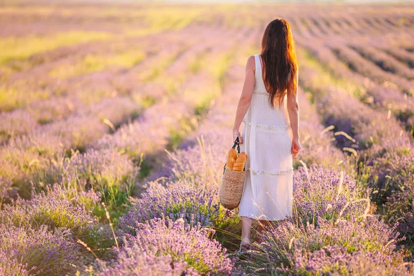 Mujer en el campo de flores de lavanda al atardecer en vestido blanco y sombrero —  Fotos de Stock