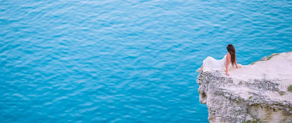 Туристическая женщина на открытом воздухе на краю скалы на берегу моря — стоковое фото