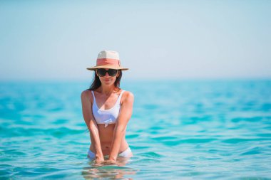 Genç ve güzel bir kadın tropik deniz kıyısında eğleniyor. Mutlu kız arka planda mavi gökyüzü ve denizdeki turkuaz su