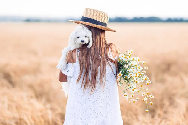 Feliz niño en el campo de trigo. Hermosa chica en vestido blanco en un sombrero de paja con trigo maduro en las manos — Foto de Stock