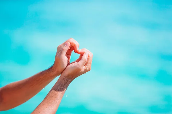 Ženské ruce v podobě srdce proti tyrkysovému moři — Stock fotografie