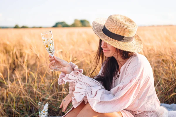 Rückansicht eines Mädchens im Weizenfeld. Schöne Frau im Kleid mit Strohhut und reifem Weizen in den Händen — Stockfoto