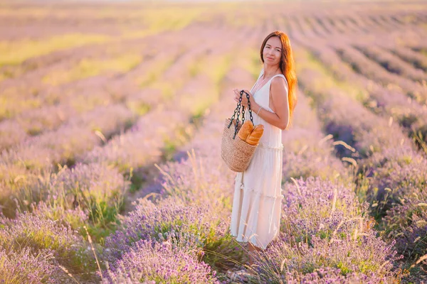 Mujer en el campo de flores de lavanda al atardecer en vestido blanco y sombrero —  Fotos de Stock
