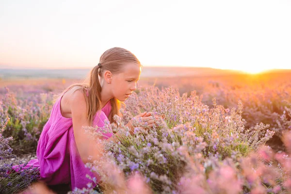可愛いです女の子でラベンダーの花のフィールドで日没で紫のドレス — ストック写真