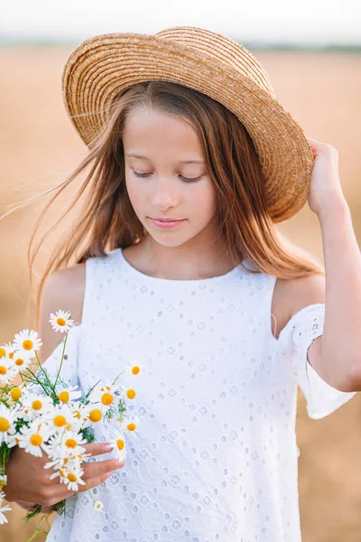 Šťastné dítě na pšeničném poli. Krásná dívka v bílých šatech v slamníku se zralou pšenicí v rukou — Stock fotografie
