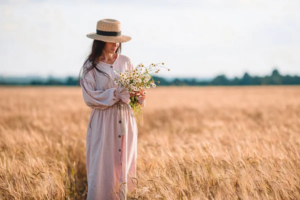 Visão traseira da menina no campo de trigo. Mulher bonita no vestido em um chapéu de palha — Fotografia de Stock