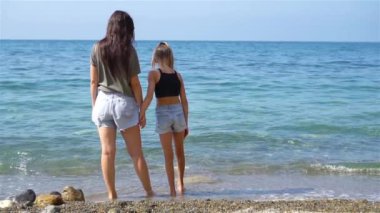 Güzel anne ve kız sahilde yaz tatilinin tadını çıkarıyorlar.
