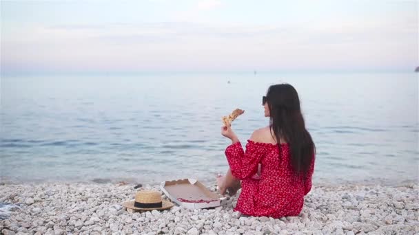 Жінка має пікнік з піцою на пляжі — стокове відео