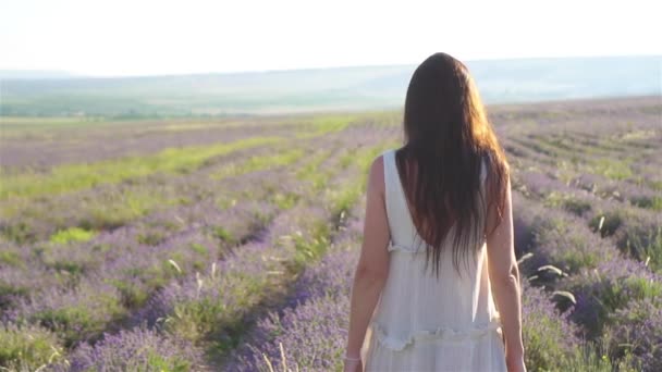 Kvinne i lavendelblomster åker ved solnedgang i hvit kjole og hatt – stockvideo