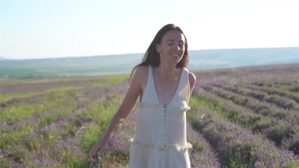 Kobieta w lawendzie kwiaty pole o zachodzie słońca w białej sukience i kapeluszu — Wideo stockowe