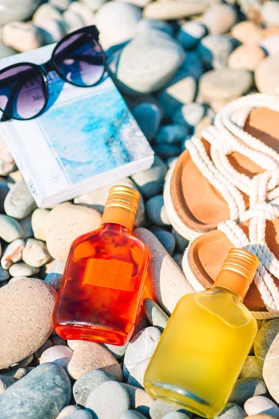 Sombrero de playa en libro abierto con protector solar y zapatos en la playa de guijarros —  Fotos de Stock