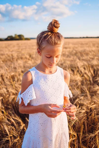 Glückliches Kind im Weizenfeld. Schöne Mädchen in weißem Kleid mit Strohhut und reifem Weizen in den Händen — Stockfoto