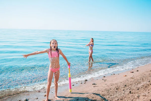 Küçük kızlar yaz tatilinde tropik plajda eğleniyorlar. Birlikte oynuyorlar.