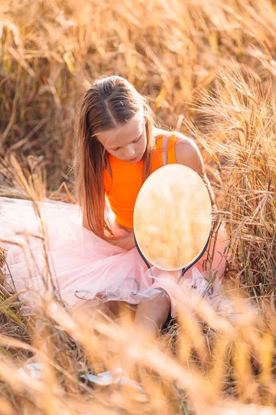 Liebenswertes Mädchen im Weizenfeld an einem warmen und sonnigen Sommertag — Stockfoto