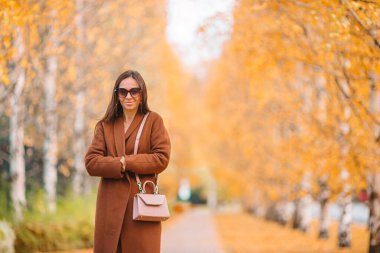 Sonbahar konsepti: Sonbahar parkında sonbahar yaprakları altında kahve içen güzel bir kadın.