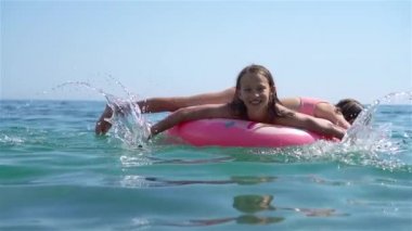 Denizdeki şişme şiltenin üzerinde sevimli bir kız.