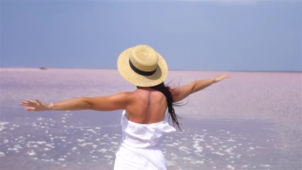 Donna in cappello cammina su un lago salato rosa in una giornata estiva soleggiata. — Video Stock