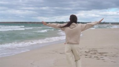 Plajda beyazlar içindeki genç kadın.