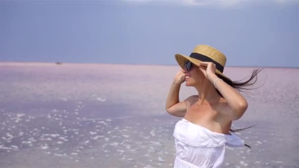 모자를 쓴 여자가 화창 한 여름날 분홍색 소금 호수 위를 걷고 있다. — 비디오